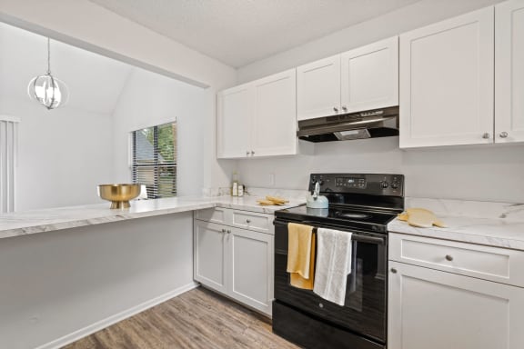 a white kitchen with black appliances and white cabinets