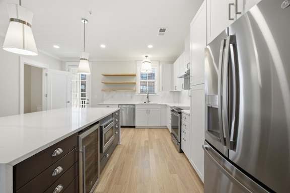 A modern kitchen with stainless steel appliances and wooden floors.