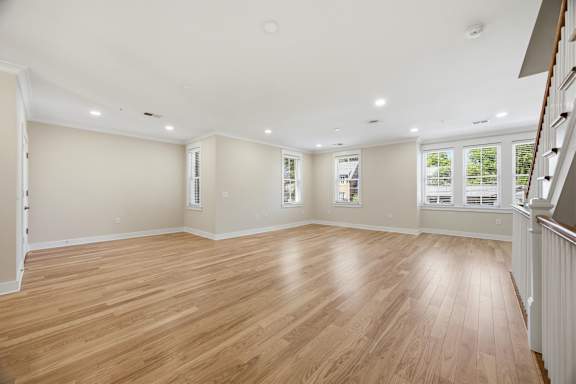 A spacious room with wooden flooring and white walls.