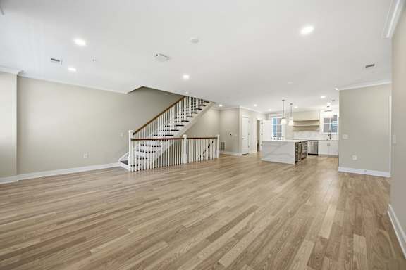 A spacious room with wooden flooring and a staircase.