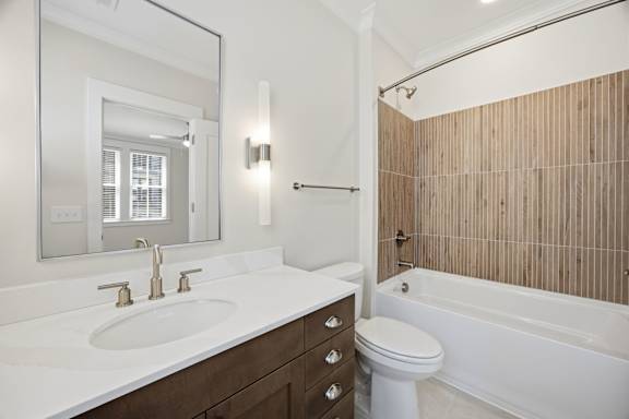 A white sink with gold faucets is in a bathroom with a white toilet and a white bathtub.
