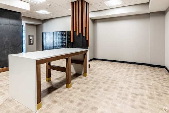 A white reception desk with gold legs in a room with a black wall and a tan carpet.