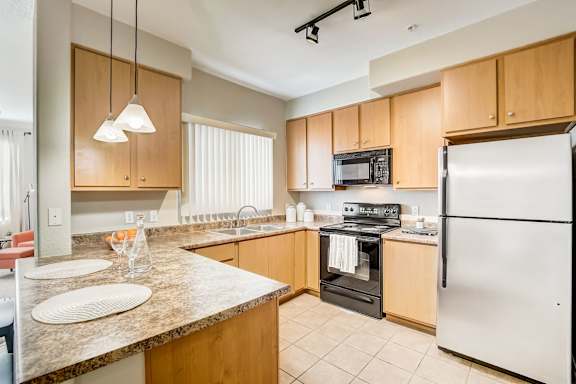A kitchen with a refrigerator, oven, microwave, and sink at Adiamo Palm Valley, Goodyear, 85395