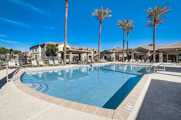 A large swimming pool surrounded by palm trees and lounge chairs at Adiamo Palm Valley, Goodyear