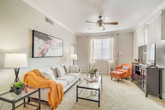 A living room with a white couch, a glass coffee table, and a ceiling fan at Adiamo Palm Valley, Goodyear, Arizona