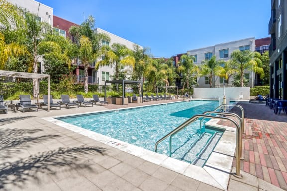 a swimming pool with chairs and a building in the background