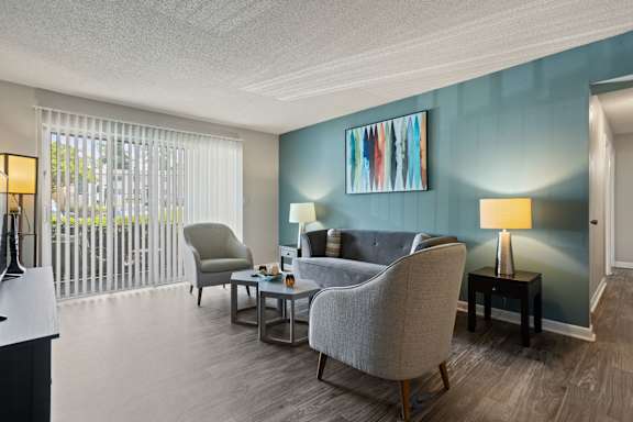 A living room with a grey chair and a blue wall.