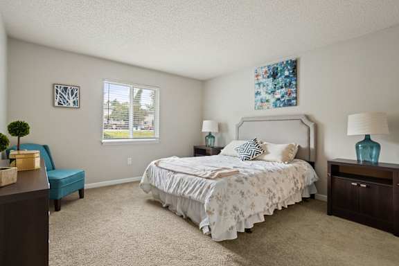 A bedroom with a large bed and a blue chair.