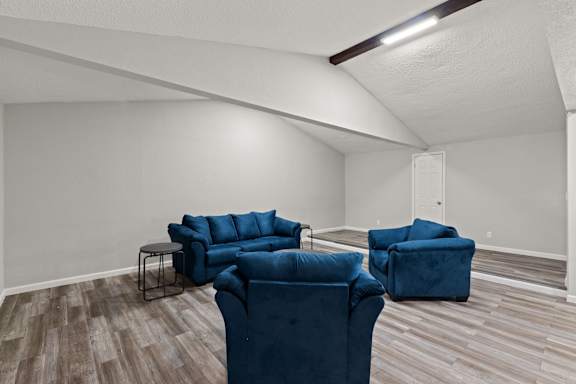 A living room with blue couches and a white wall.