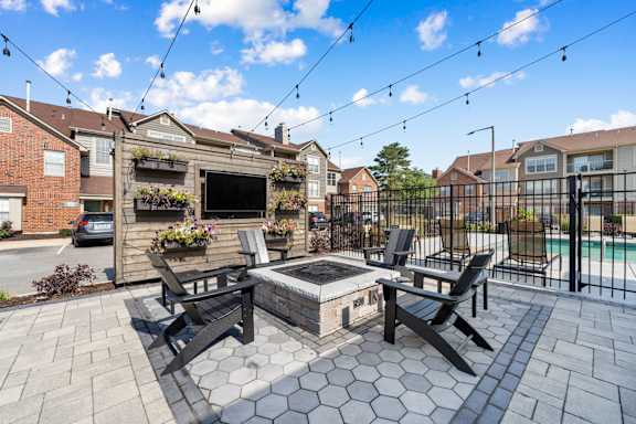 A patio with a hot tub and chairs is surrounded by a black fence.