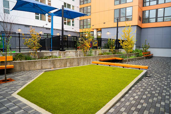 a courtyard with benches and grass in front of a building
