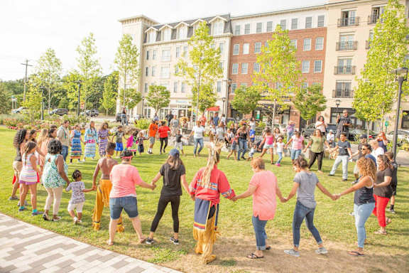 A group of people are dancing in a park.
