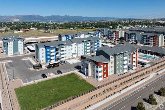 A large apartment complex with a parking lot in front.