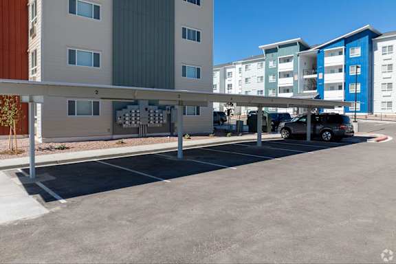 A parking lot in front of a multi-story apartment building.