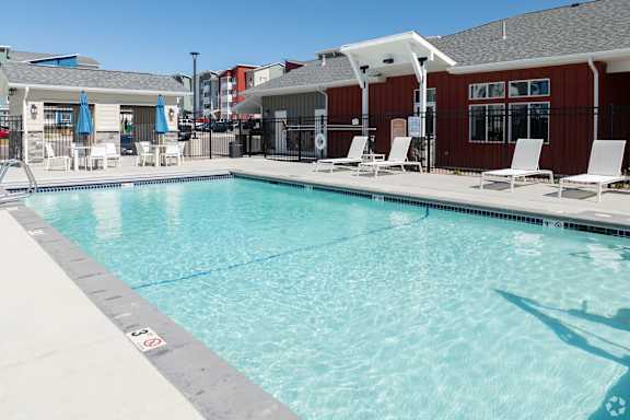 A swimming pool with a white fence and a red building in the background.