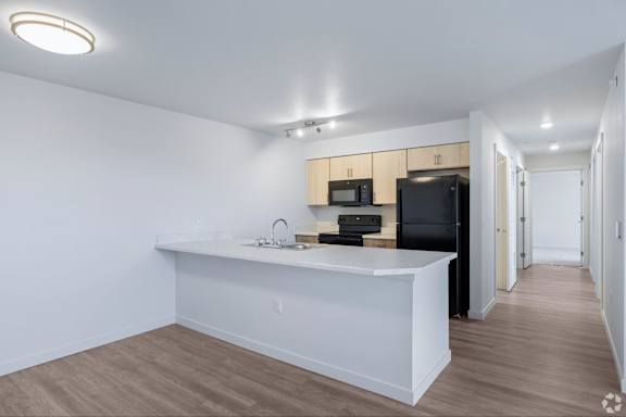 A kitchen with a black refrigerator, microwave, and oven.