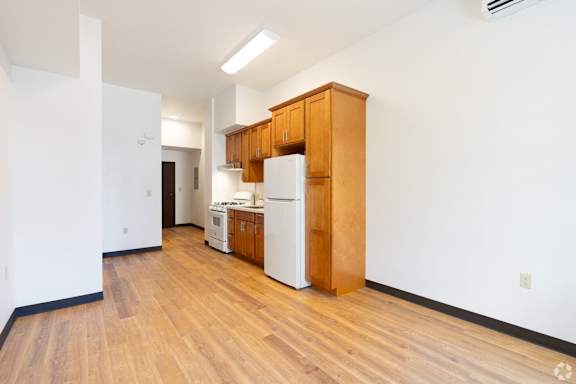 a kitchen with white appliances and wood flooring in an empty apartment