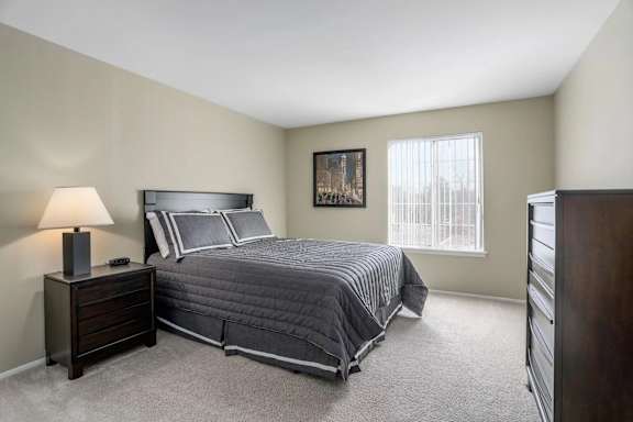 A bedroom with a bed, nightstand, and a painting on the wall.