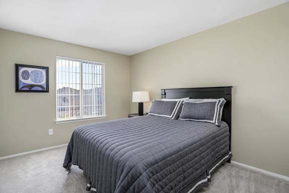 A bedroom with a large bed and a picture on the wall.