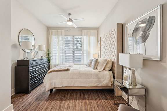 A bedroom with a bed, dresser, and a ceiling fan.