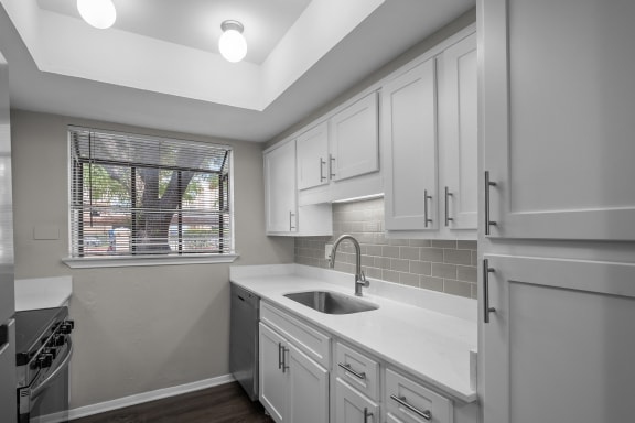 an empty kitchen with white cabinets and a window