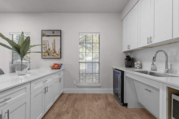 A kitchen with white cabinets and a wooden floor.
