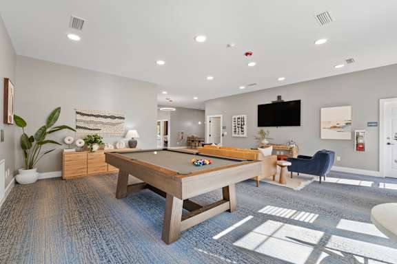 A room with a pool table and a television.