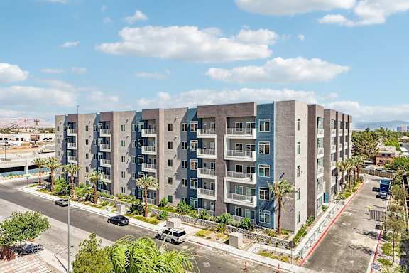 A modern apartment building with a parking lot in front.