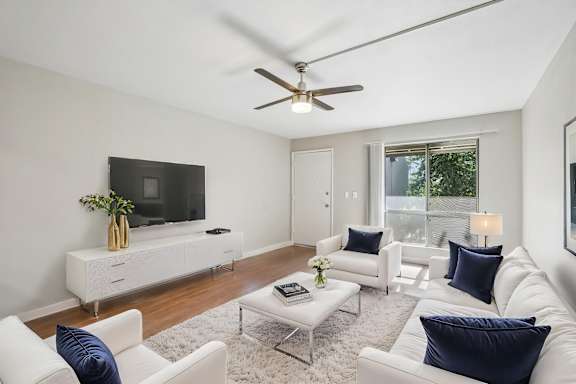 A living room with white furniture and a flat screen TV.