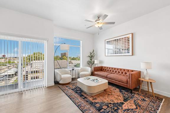 A living room with a brown couch and a ceiling fan.