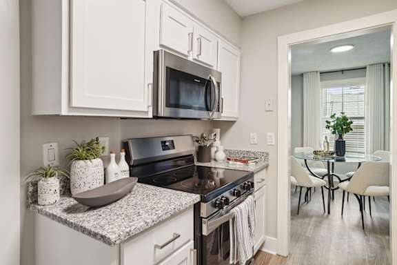 A kitchen with white cabinets and a black countertop.