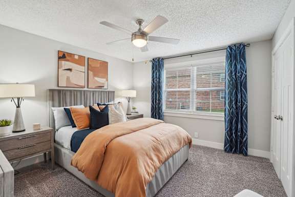 A bedroom with a bed, nightstand, and window.