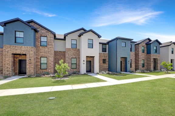 a row of houses with a sidewalk and grass