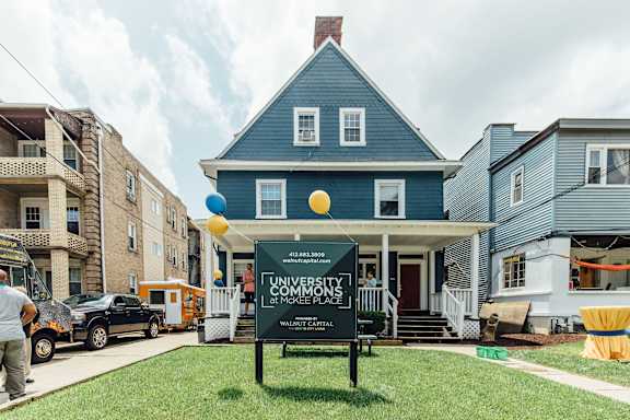 A blue house with a sign that says "University Commons" in front of it.
