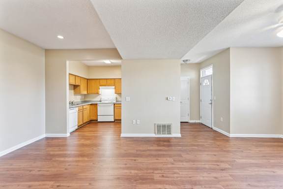 A kitchen and Dining room with white walls and wooden floors.