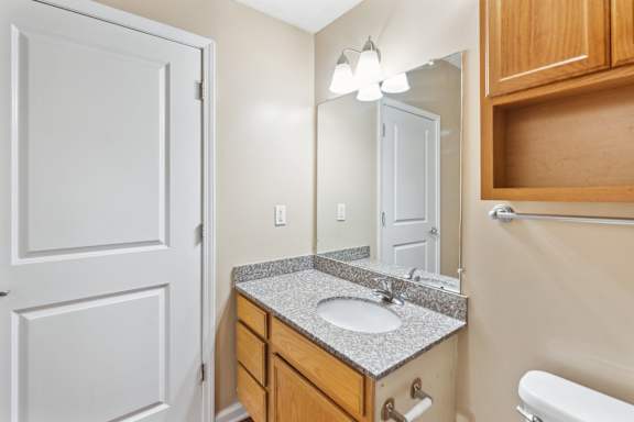 A bathroom with a sink, mirror, and toilet.