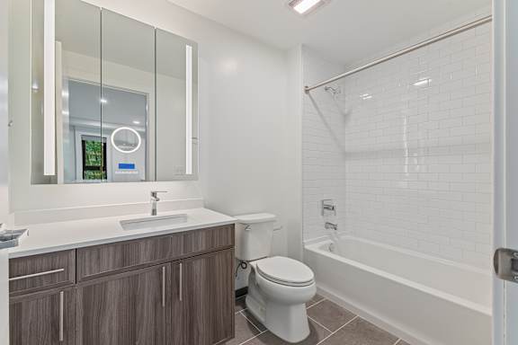 A modern bathroom with a white sink and a white toilet.at Essen Apartments, Alexandria, VA