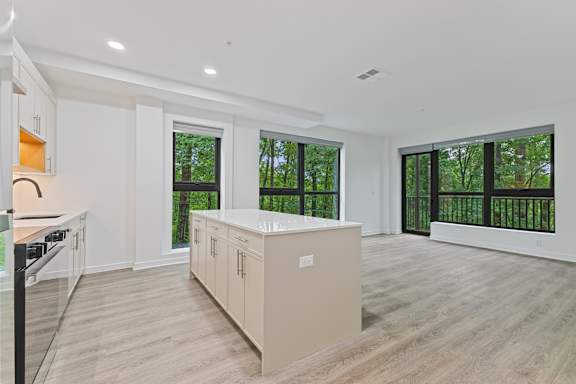 A spacious kitchen with white cabinets and a large island.at Essen Apartments, Alexandria