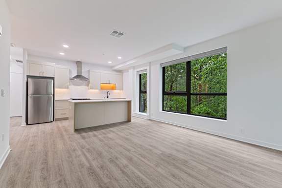 A kitchen with a refrigerator, stove, and island with a countertop and sink.at Essen Apartments, Alexandria