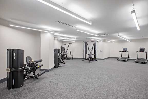 A gym with a variety of equipment including treadmills, weights, and exercise machines.