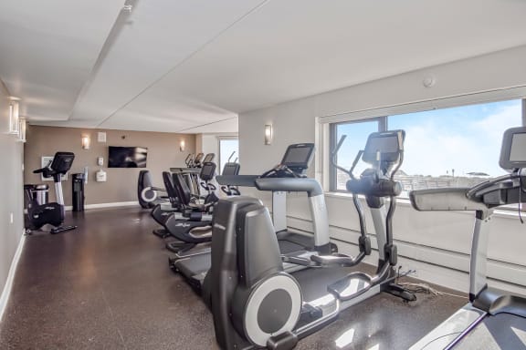 an exercise room with cardio equipment and a view of the city