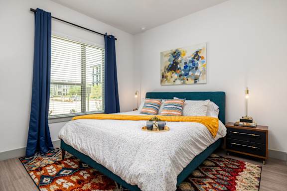 A bedroom with a large bed and a painting on the wall.