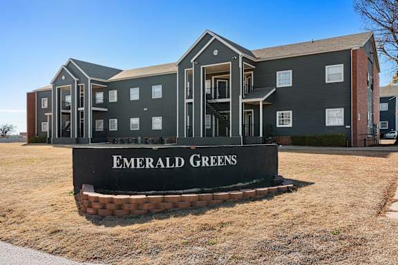 an apartment building with a blue sky in the background at Emerald Greens, Norman, OK 73072