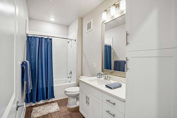 A white bathroom with a blue shower curtain.
