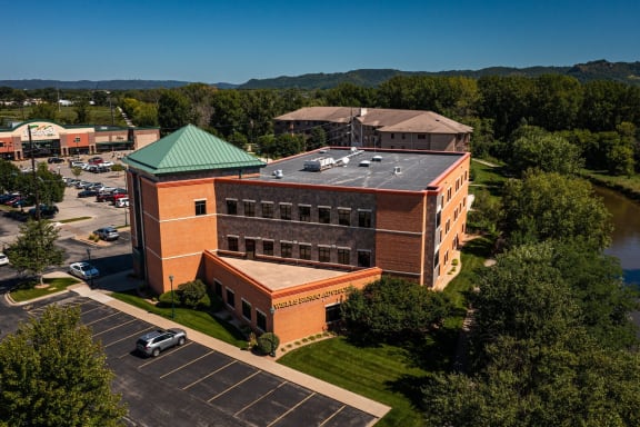 a brick building with a green roof and a parking lot
