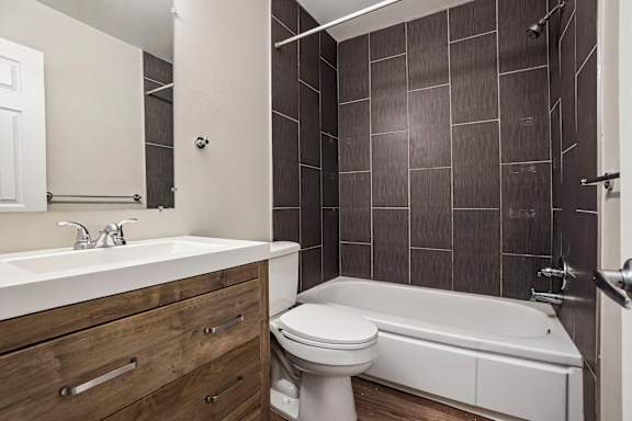 A white toilet sits in a bathroom with a white sink and a white bathtub.