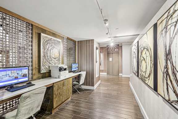 a home office with two computers on a desk and a wood floor