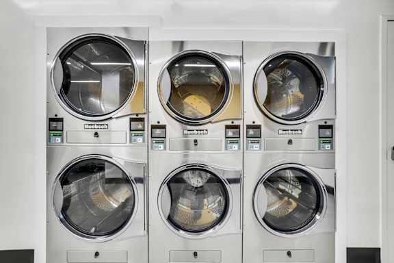 Four front loading washing machines are lined up in a row.