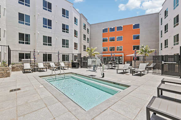A pool surrounded by chairs and a fence.
