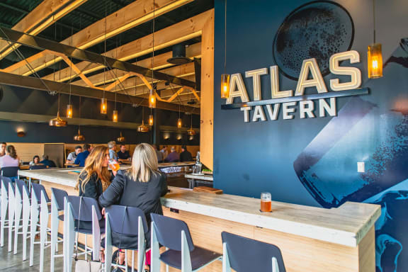 a couple of people sitting at a bar at atlas tavern